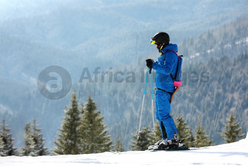 Man skiing on snowy hill in mountains, space for text. Winter vacation