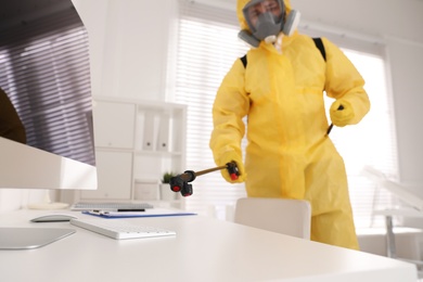 Man in protective suit sanitizing doctor's office. Medical disinfection