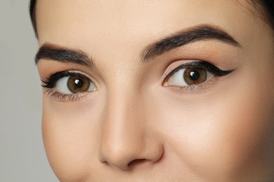 Photo of Young woman with beautiful eyebrows on grey background, closeup