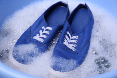 Washing pair of sport shoes in plastic basin, closeup
