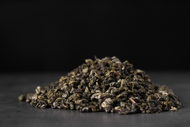 Heap of dried green tea leaves on grey table, closeup