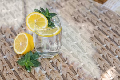Photo of Refreshing water with lemon and mint on glass table, space for text