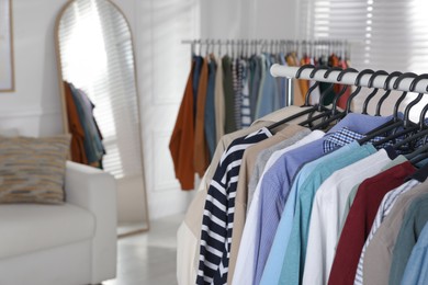 Photo of Rack with stylish clothes indoors, closeup. Fast fashion