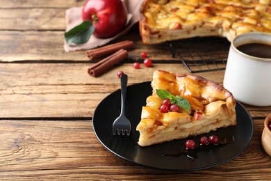 Slice of traditional apple pie with berries served on wooden table