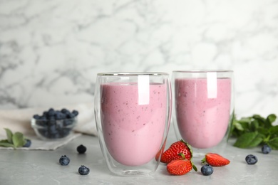 Tasty milk shakes and fresh berries on grey marble table