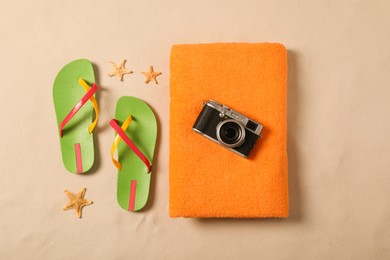 Beach towel, camera, flip flops and starfishes on sand, flat lay