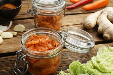 Delicious kimchi with Chinese cabbage and ingredients on wooden table, closeup