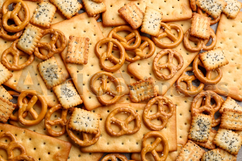 Many delicious crackers as background, top view