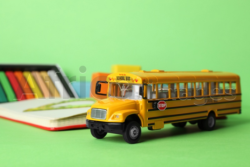 School bus model and stationery on green background. Transport for students