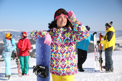 Young woman with snowboard at ski resort. Winter vacation