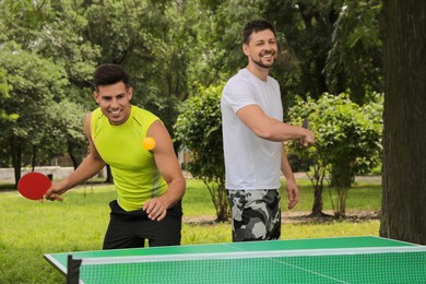 Men playing ping pong in park on summer day