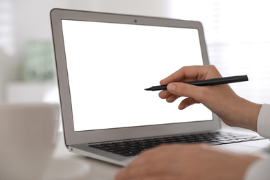 Woman pointing at modern laptop with blank screen, closeup