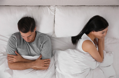 Unhappy couple with relationship problems after quarrel in bed, above view