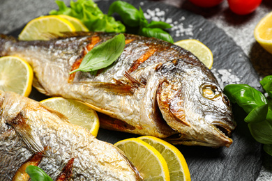 Delicious roasted fish with lemon on slate plate, closeup