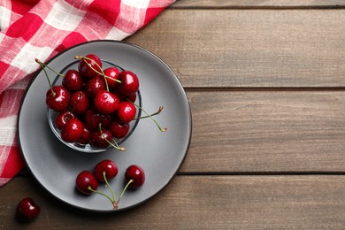 Wet red cherries on wooden table, flat lay. Space for text
