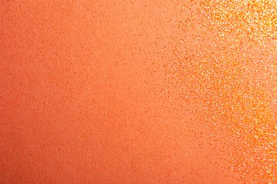 Shiny bright glitter on coral background, flat lay. Space for text