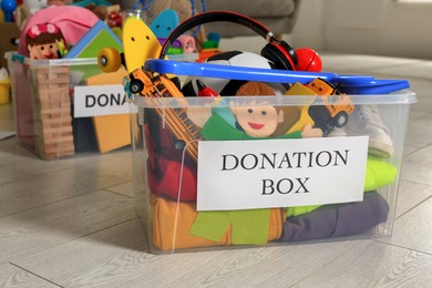 Donation boxes with different child toys on floor indoors