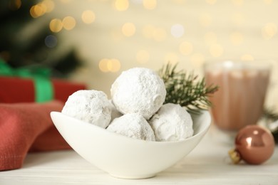 Photo of Ceramic bowl with tasty Christmas snowball cookies on white table, closeup