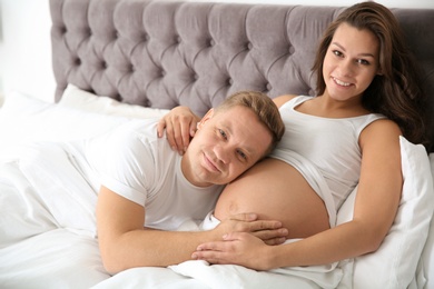Pregnant woman with her husband in bedroom. Happy young family