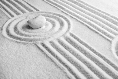White stone on sand with pattern. Zen, meditation, harmony