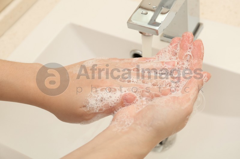 Woman washing hands with antiseptic soap in bathroom, closeup