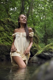 Beautiful young woman in mountain river in forest