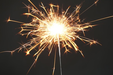 Bright burning sparkler on black background, closeup