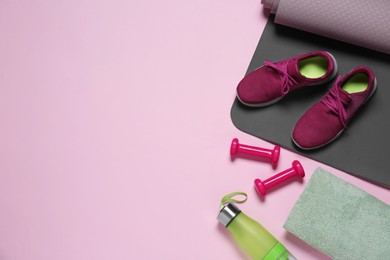 Photo of Exercise mat, dumbbells, shoes, towel and bottle of water on pink background, flat lay. Space for text