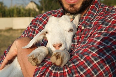 Man with baby goat at farm, closeup. Animal husbandry