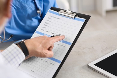 Photo of Doctor showing medical card to patient at table in clinic, closeup