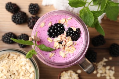 Photo of Delicious blackberry smoothie, oatmeal and berries on wooden table, flat lay