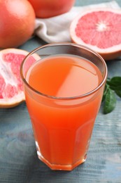 Tasty freshly made grapefruit juice on blue wooden table