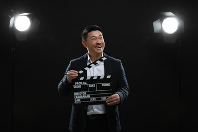 Photo of Happy asian actor with clapperboard on stage. Film industry