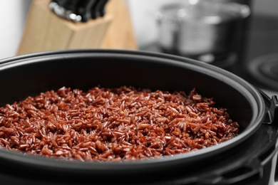 Modern multi cooker with boiled brown rice in kitchen, closeup