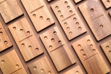 Set of wooden domino tiles on brown background, flat lay