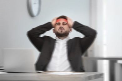 Man suffering from migraine at workplace in office