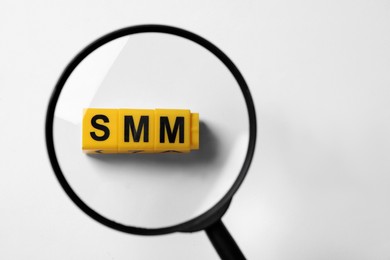 Photo of Top view through magnifying glass on yellow cubes with letters SMM, white background