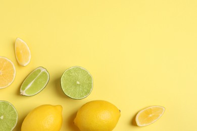 Fresh ripe lemons and limes on yellow background, flat lay. Space for text