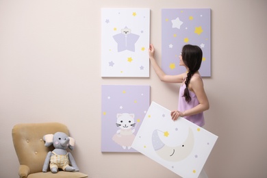 Decorator hanging pictures on pink wall. Children's room interior design