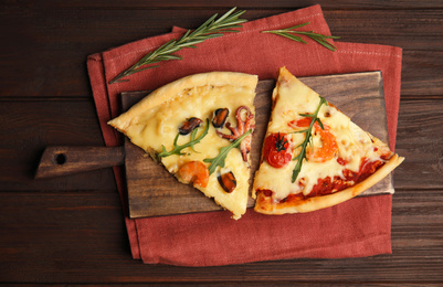 Pieces of delicious seafood pizza on wooden table, flat lay