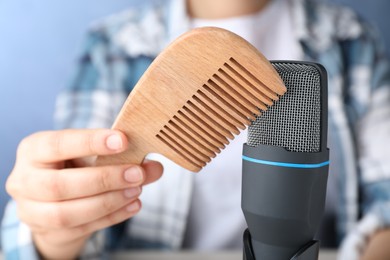 Woman making ASMR sounds with microphone and wooden comb, closeup