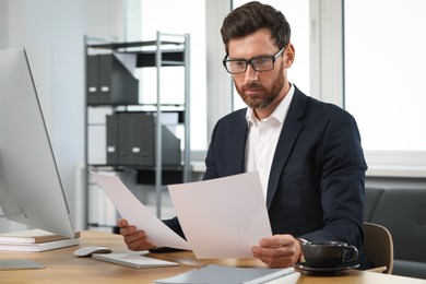 Handsome bearded man working with documents at table in office