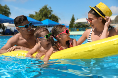 Happy family with inflatable mattress in swimming pool. Summer vacation