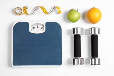 Composition with scales, fruits, tape measure and dumbbells on white background, top view