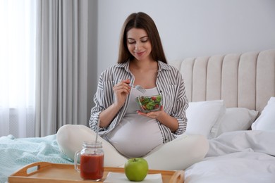 Pregnant woman eating breakfast on bed at home. Healthy diet
