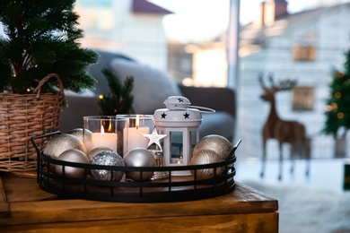 Burning candles, lantern and Christmas balls on wooden table indoors