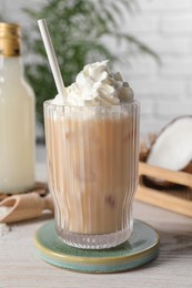 Photo of Bottle of delicious syrup, glass of iced coffee, coconut and flakes on white wooden table