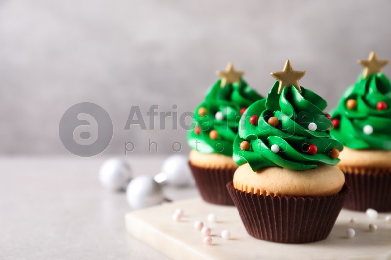 Christmas tree shaped cupcakes on light grey table. Space for text