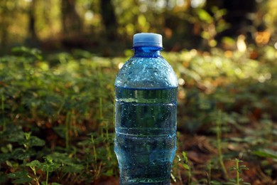 Photo of Plastic bottle of fresh water outdoors, closeup