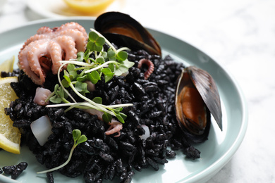Delicious black risotto with seafood on table, closeup